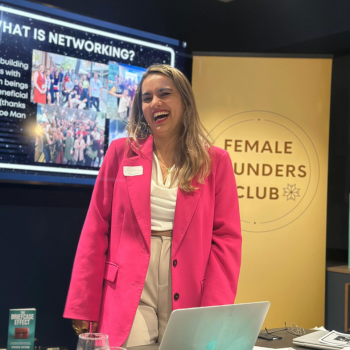Woman in a bright pink blazer smiling while presenting at the Female Founders Club event.
